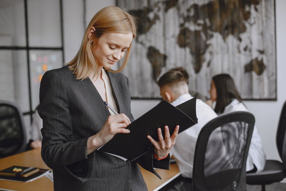 Confident businesswoman in formalwear taking notes during a team meeting in a modern office.